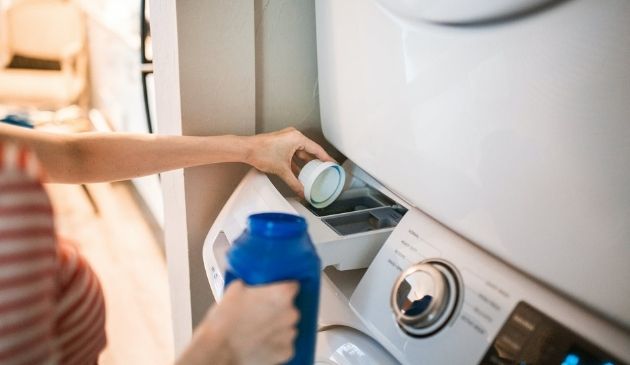 woman adding liquid to washing machine