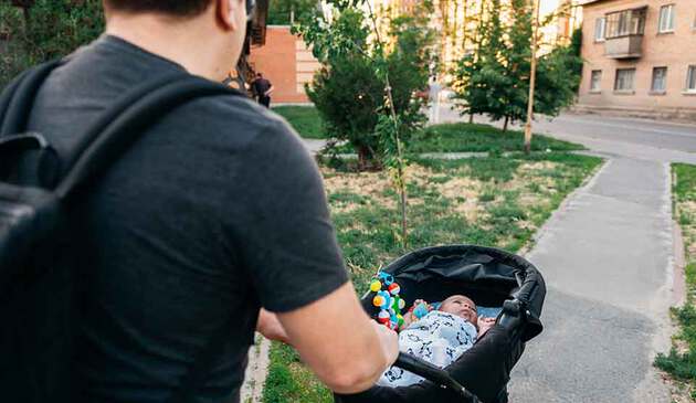 dad pushing newborn in pushchair