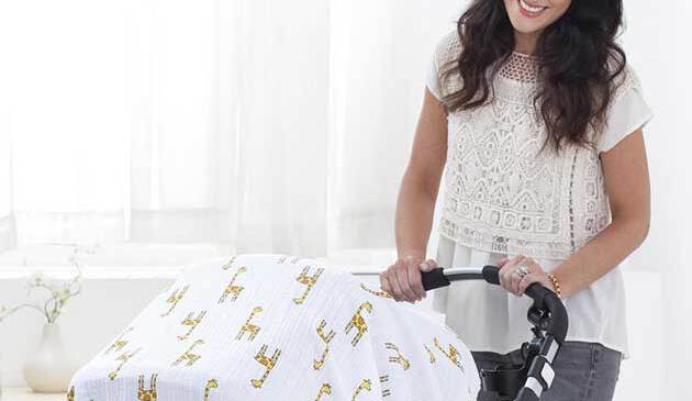 Mum pushing a pushchair covered by a swaddle