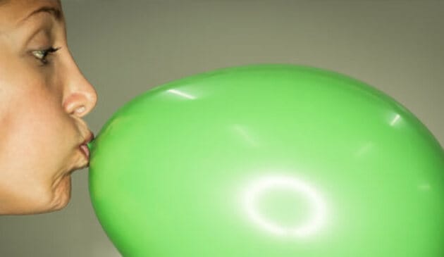 Woman blowing up balloon