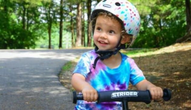 child riding scooter wearing bike helmet