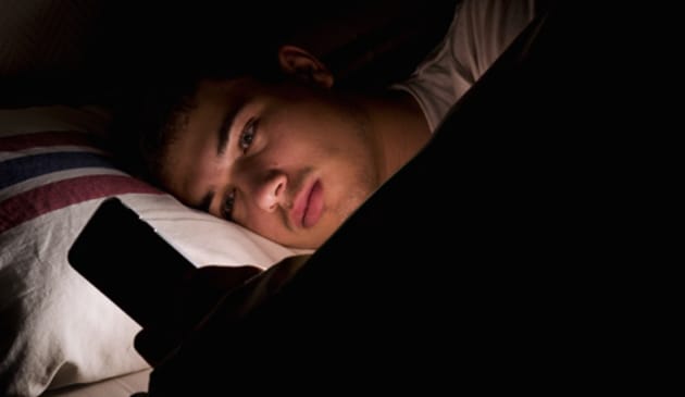 sad boy in bed looks at phone