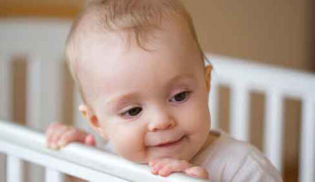 Eight month old standing up in cot