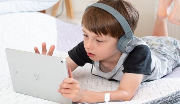 child wearing headphones and playing on tablet