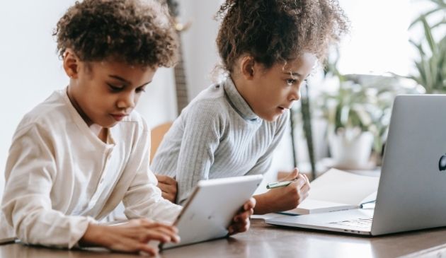 two children using a kids laptop and tablet