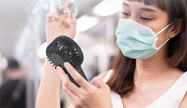 一个女人在公共场合拿着手提电扇