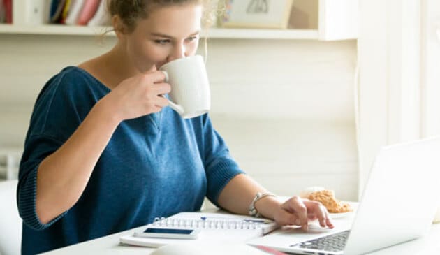 Woman looking at laptop drinking coffee