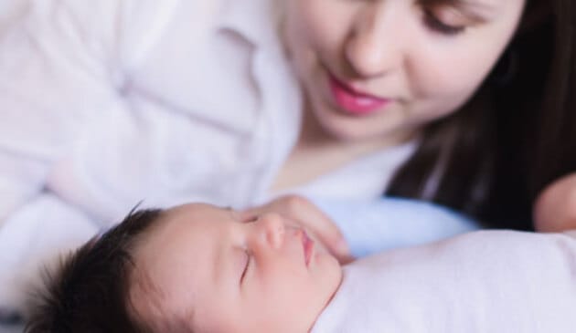 Woman looking down at a sleeping baby