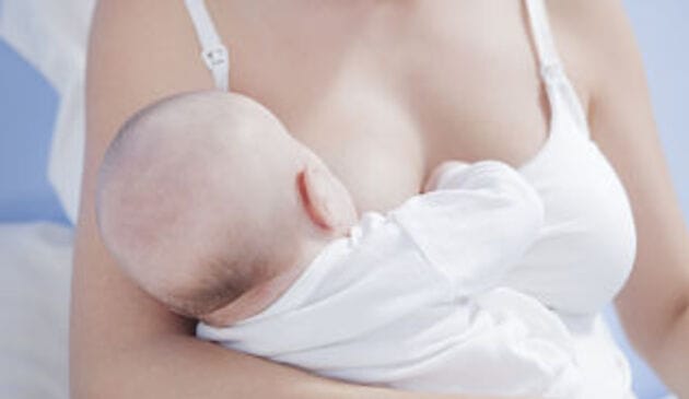 Woman's torso breastfeeding a baby in a nursing top